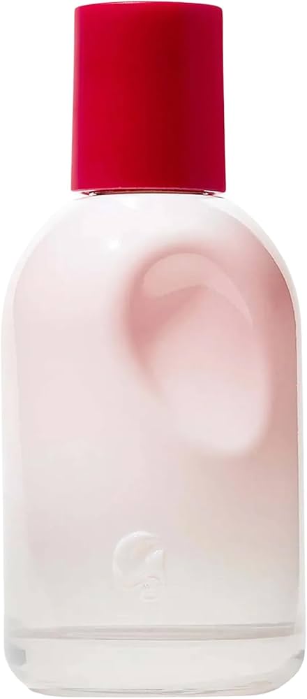 Celeste in a pale blush ribbed knit beside the soft pink rounded river-stone Glossier You perfume bottle on a warm pinkish-beige minimalist table