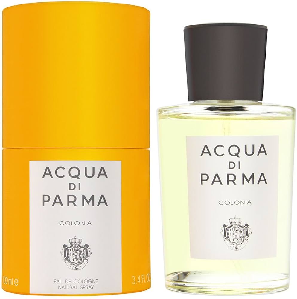 Celeste in a buttery-yellow silk blouse at a sunlit Mediterranean courtyard with an Art-Deco cylindrical pale-yellow cologne bottle and black label band