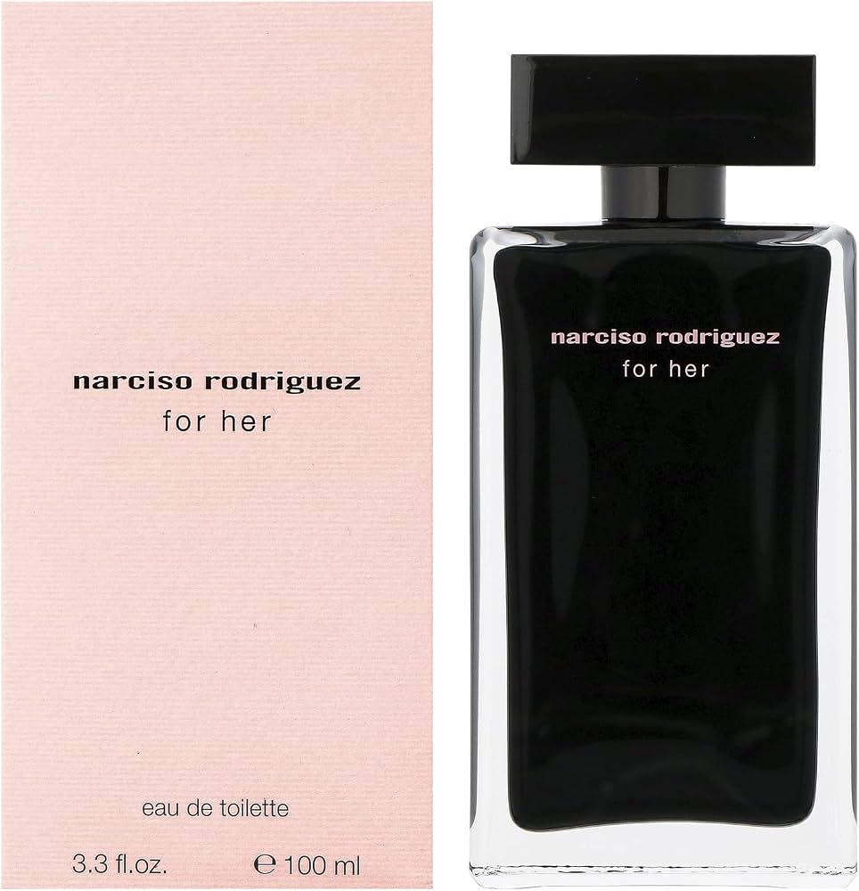 Celeste in a blush-pink silk slip leaning over a marble table with a soft pink rounded-rectangle perfume bottle topped by a flat black disc cap